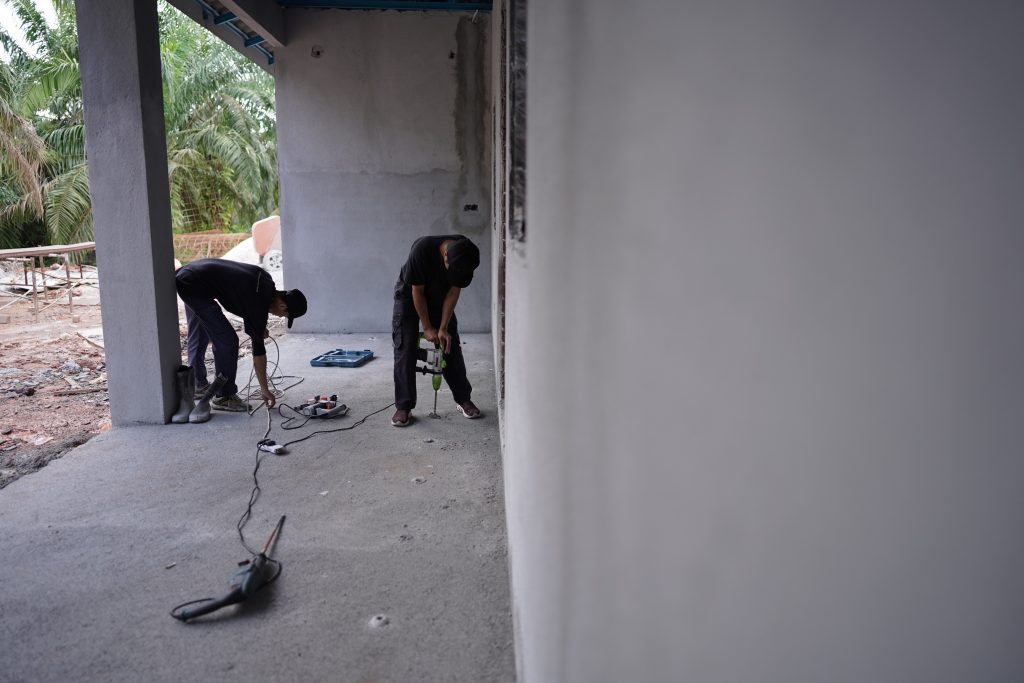 Two pest control technicians performing termite treatment in Kuala Lumpur property